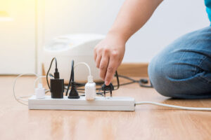 A person plugging a device into a power strip.