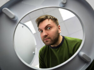 A man with a puzzled expression looking into a toilet bowl.