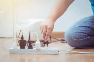 A person plugging devices into a power strip.